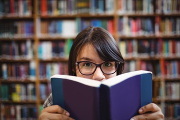 Female student holding book in college library