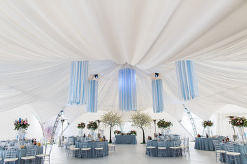 White blooming trees stand in a white pavilion decorated for wed