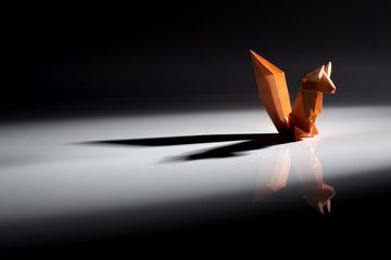 Origami art, colored squirrels isolated over a wooden background