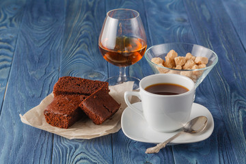 Homemade chocolate brownie and a white mug cup on wood table.