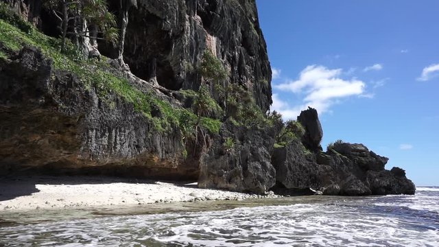 Eroded limestone cliff with cave on the sea shore of Rurutu island, motionless, south Pacific ocean, Austral archipelago, French Polynesia

