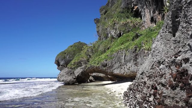 Eroded limestone cliff with a natural arch on the shore of Rurutu island, south Pacific ocean, Austral archipelago, French Polynesia
