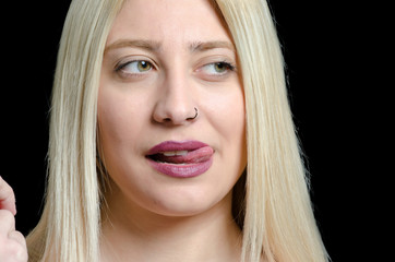 Naklejka premium Woman with green eyes and sexy mouth licks her top lip, black background