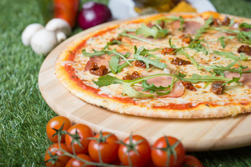 Pizza with fresh ingredients like sun dried tomatoes, rucola and ham