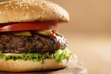 closeup fresh homemade burger with marble beef, cheese and vegetables on olive board