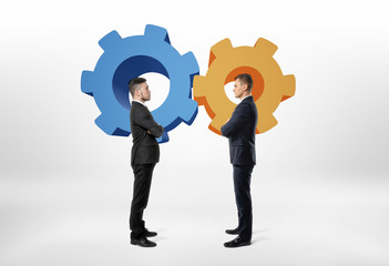 Two businessmen standing opposite to each other with cartoon cogwheel.