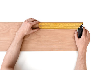 Man's hands measuring wooden plank with a iron ruler, isolated on white background
