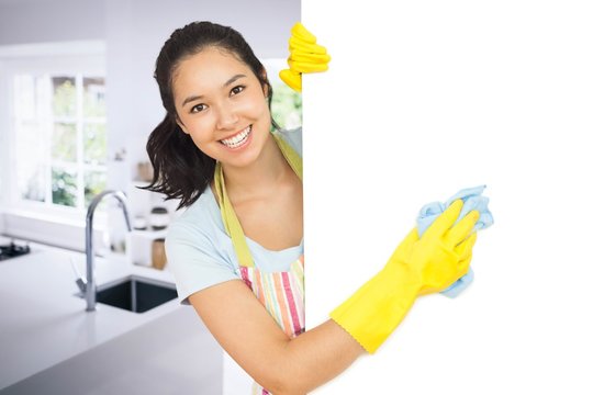 Composite image of cheerful woman cleaning white surface