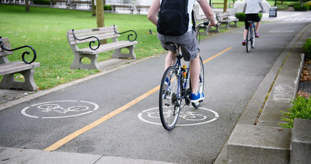 Urban biking. Young couple riding bicycle in city park. Healthy summer concept lifestyle