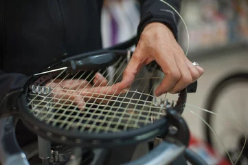 Fototapeten Stringing Machine. Close up of tennis stringer hands doing racket stringing in his workshop © guruXOX