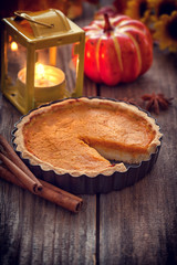 Thanksgiving pumpkin pie with lantern on wooden background