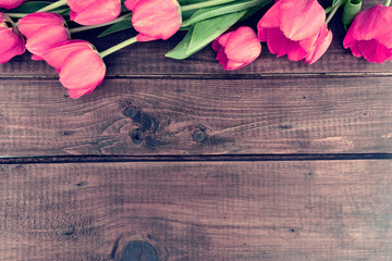Row of tulips on wooden background with space for message. 