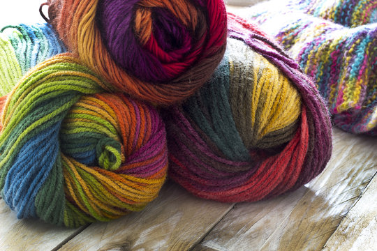 Colorful skeins of wool and sweater on wooden background