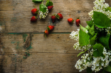 Fototapeta na wymiar Strawberries and white lilac flowers