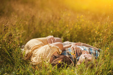 couple of man and woman dressed in country style  lying on the field of flowers