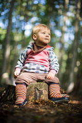 Baby sitzt auf dem Baumstumpf