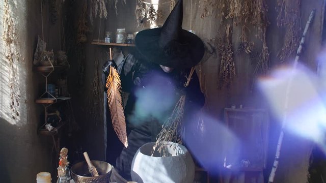 Halloween witch preparing potion in the boiler
in the foreground glimmering magical lights