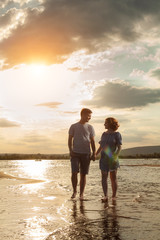 Happy couple is walking on the beach.