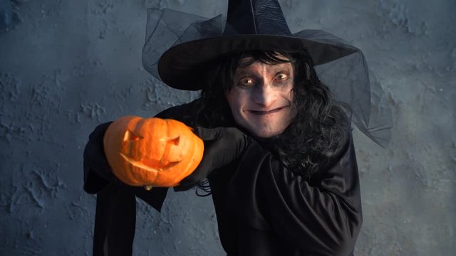 Halloween witch holding a pumpkin