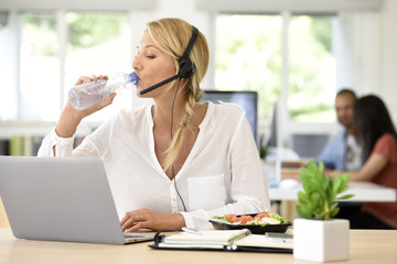 Busy customer service manager eating lunch in office