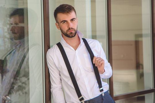 Sexy businessman with beard is wearing suspenders