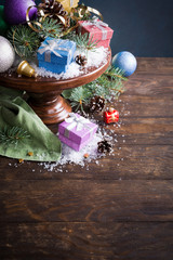 Christmas greeting card with gifts, christmas tree and snow on wooden cake stand. With copy space for text.