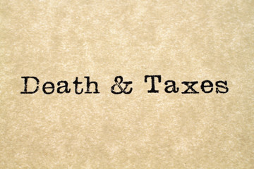 A close up image of the word "death & taxes" from a typewriter on antique paper