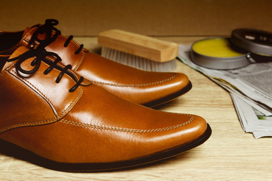 Closeup leather shoes with cleaning sets on wood table