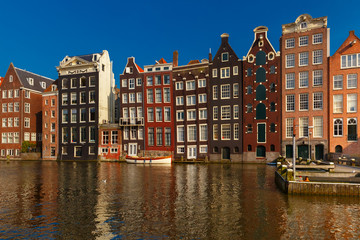 Naklejka premium Beautiful typical Dutch dancing houses at the Amsterdam canal Damrak in sunny day, Holland, Netherlands.