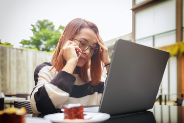 Young asian women using laptop and smartphone contact to clients while working at home