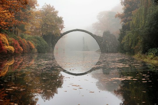 Rakotz Bridge Over Calm Lake Against Sky At Park During Autumn