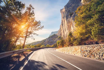 Keuken foto achterwand Zalmroze Asphalt road. Colorful landscape with beautiful mountain road with a perfect asphalt. High rocks, trees, blue sky at sunrise in summer. Vintage toning. Travel background. Highway at mountains