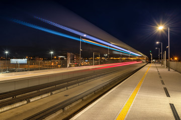 Fototapeta na wymiar Night view. Train departing from railway station platform with motion blur effect.