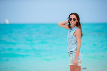 Young beautiful woman during tropical beach vacation. Enjoy summer vacation alone on the beach with frangipani flowers in her hair