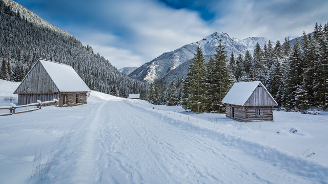 Wooden cottages covered by snow in winter at sunrise, Tatra Mountains, Poland