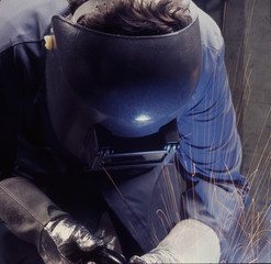 man welding with torch, helmut and gloves - obrazy, fototapety, plakaty