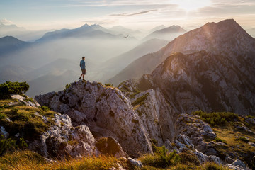 Man standing on a mountain summit at sunset