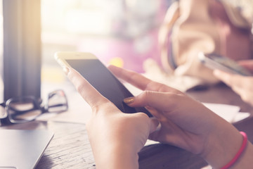 Young woman hand holding using smartphone in coffee shop, vintag