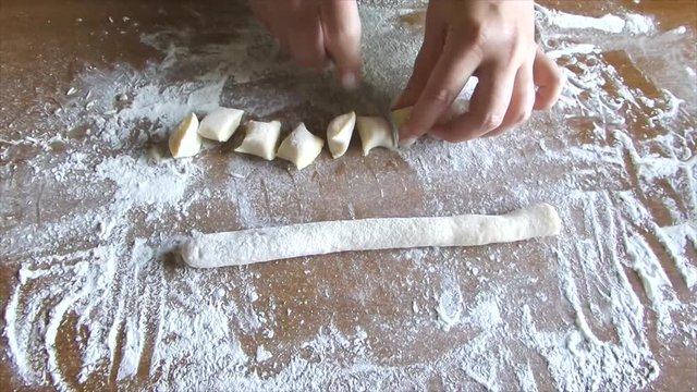 Woman hands making potato gnocchi on wood table with flour.