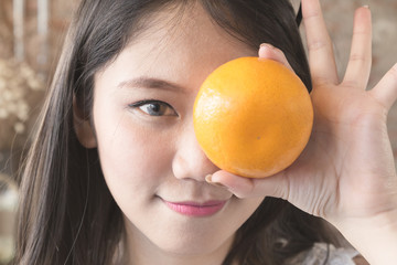 Closeup face of Young asian woman smiling and holding orange, soft vintage