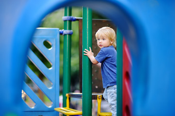 Fototapeta premium Cute toddler boy having fun on outdoors playground