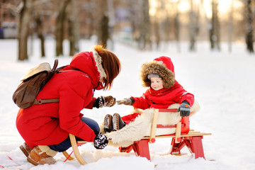Fototapeta na wymiar Portrait of beautiful toddler boy and his mother having fun in snowy park