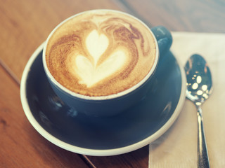 Cappuccino coffee in black cup on wooden table, Soft focus, Summ
