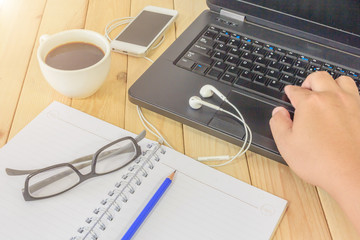 Office workplace, Man working with laptop computer, smartphone and white porcelain cup of black coffee on wood table. View from above