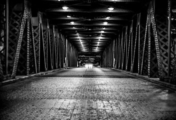 Middle of the road looking down the bridge with oncoming car - obrazy, fototapety, plakaty