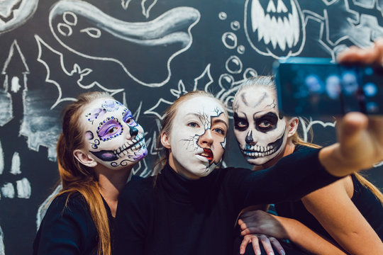 Three girls going on Halloween, grimace make selfie  a dark background with  pattern