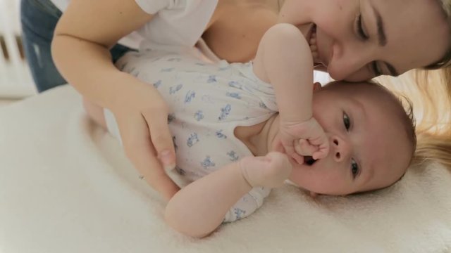 Happy young mother tickling and playing with her adorable baby boy
