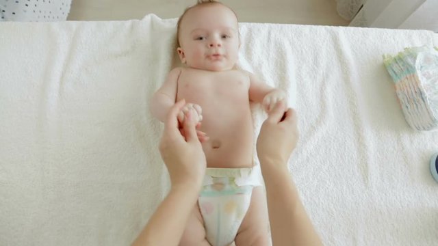 POV mother playing and touching cute 3 months old baby son lying on changing table