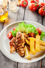 Grilled chicken breasts served with fries and fresh salad