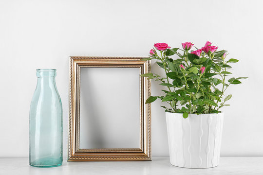 Vase with roses, bottle and photo frame on table
